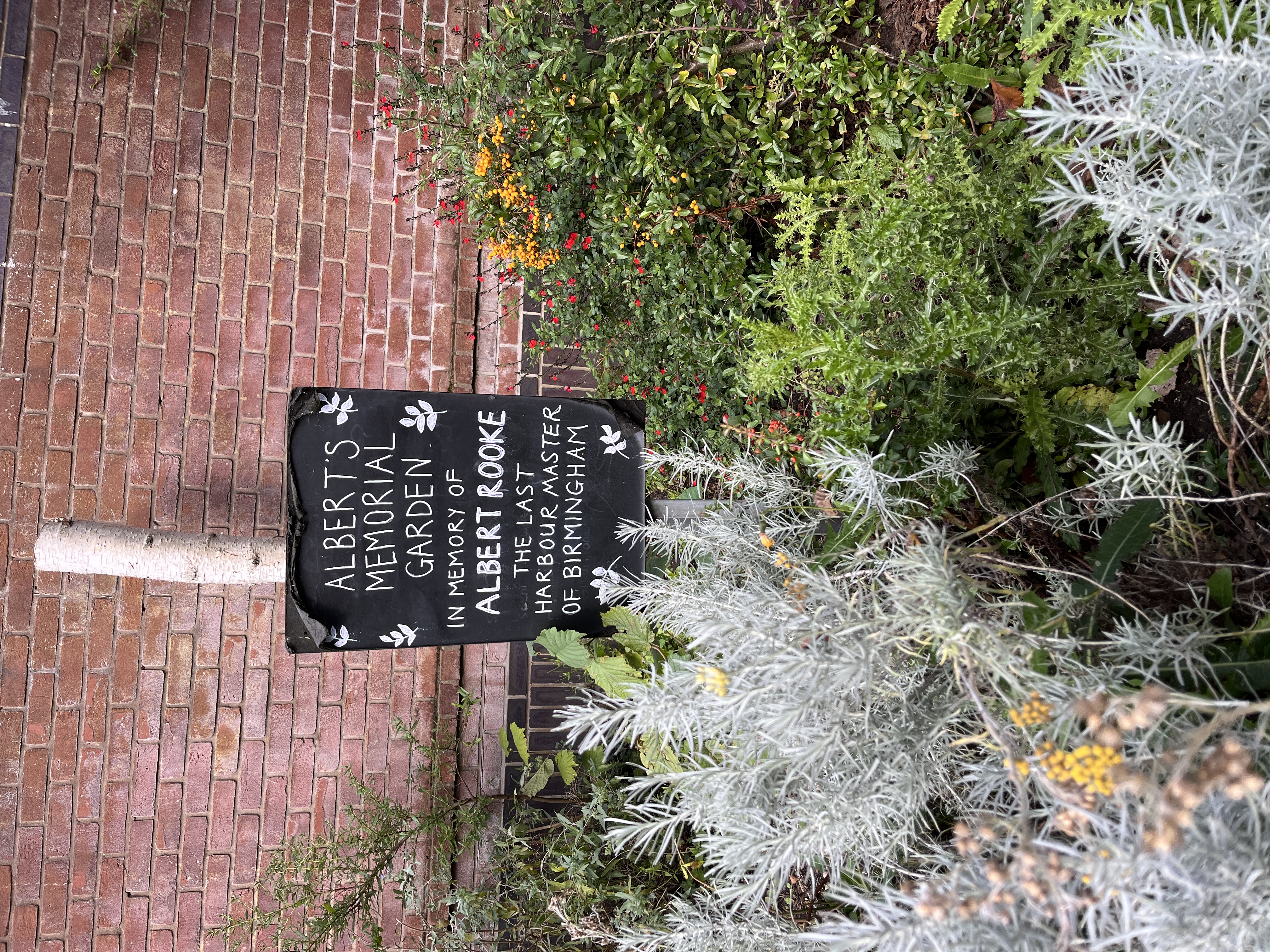a little garden along a brick wall called "albert's memorial garden"